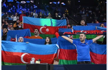 Shamil holding Azerbaijan's flag among fellow Azerbaijani soccer fans during a match