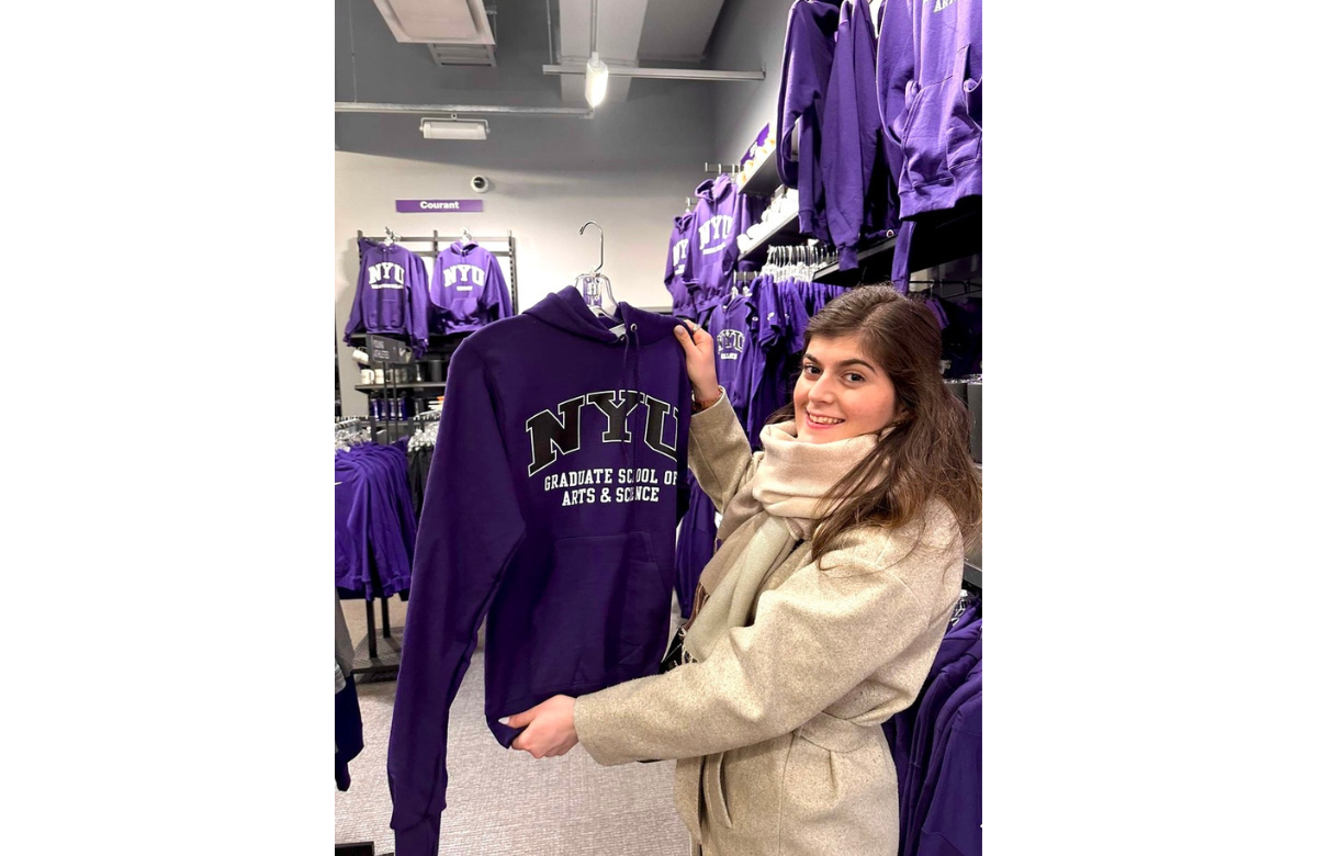 Viktoria Ivanova posing with an NYU sweatshirt at NYU's shop
