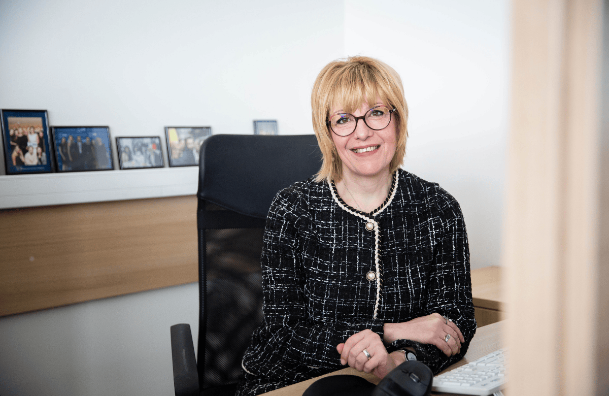 Albena Kehayova (EMBA '16) sitting on her desk at AUBG and taking about the power of community and giving back to AUBG width=